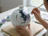 expressive green vines, golden accents and visible hand-painted brushwork on the porcelain vase