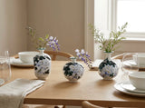 Set of three Wisteria Reverie porcelain bud vases arranged on a light-filled console table.