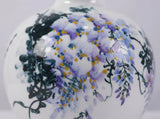 Close-up of layered lilac and violet wisteria blossoms painted by hand on glazed white porcelain