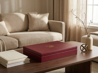 Closed burgundy mahjong case displayed on a coffee table with books and decorative home accents