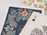 Close-up of the contrasting navy and ivory tropical botanical card backs with fine gold-tone borders