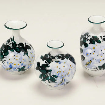 Set of three Wisteria Reverie hand-painted porcelain mini bud vases in varied rounded silhouettes.